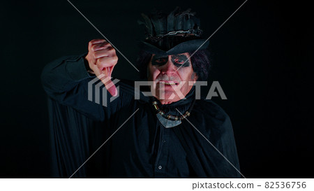 Sinister senior old man in costume of Halloween witcher showing thumbs down sign gesture dislike 82536756
