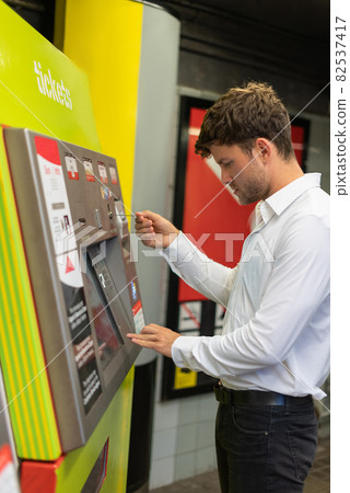 Side view of male entrepreneur inserting credit card into machine while buying ticket on subway station 82537417