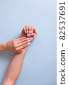 Stylish trendy female manicure. Beautiful young woman's hand with perfect pink manicure on blue background. 82537691