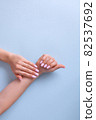 Hands of a beautiful woman on a blue background. Delicate hands with natural pink manicure, clean skin. 82537692