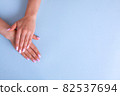 Stylish trendy female pink manicure. Beautiful young woman's hands on blue background. 82537694