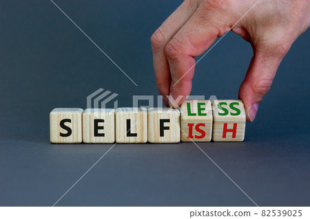 Selfish or selfless symbol. Businessman turns cubes and changes the word 'selfish' to 'selfless'. Beautiful grey background, copy space. Business, psuchological and selfish or selfless concept. 82539025