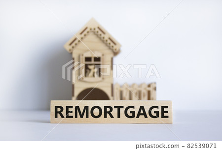 Remortgage symbol. Word 'remortgage' on wooden block. Model of a wooden house. Copy space. Business and remortgage concept. Beautiful white table, white background. 82539071