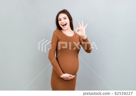 positive pregnant woman showing okay gesture against her belly at colored background. Easy and happy pregnancy. Copy space 82539227