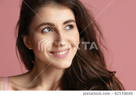 Close-up portrait of young beautiful girl without makeup isolated over pink studio background. Natural beauty concept. Close-up portrait of young beautiful girl without makeup isolated over pink studio background. Natural beauty concept. 82539688