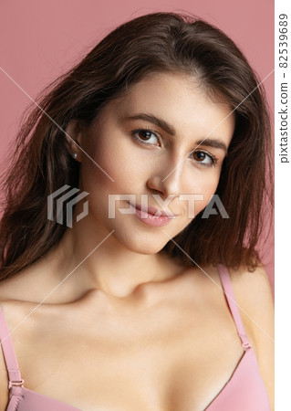 Close-up portrait of young beautiful girl without makeup isolated over pink studio background. Natural beauty concept. Close-up portrait of young beautiful girl without makeup isolated over pink studio background. Natural beauty concept. 82539689