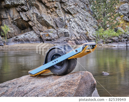 one-wheeled electric skateboard on a shore of mountain river 82539949