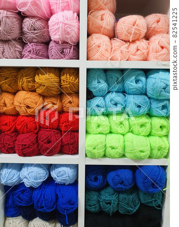 Colorful yarns of wool for knitting on shelves in the haberdashery shop. Knitwork handcraft concept 82541225