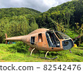 Abandoned damaged helicopter in center forest in mid of Carpathian Mountains. Disused rusty chopper without doors and wings is nothing but aged scrap of old vehicle among green nature of Carpathians 82542476