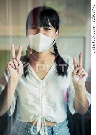 asian woman wearing protection face mask standing behind home mirror door sign victory hand asian woman wearing protection face mask standing behind home mirror door sign victory hand 82563773