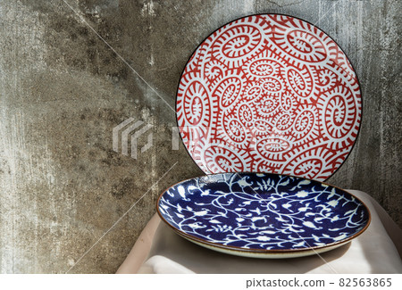 Two ceramics plates on pink table cloth. 82563865