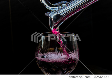 Flat lay composition with Pouring red wine from pitcher into the wineglass : traditional winemaking and wine tasting concept. 82564632