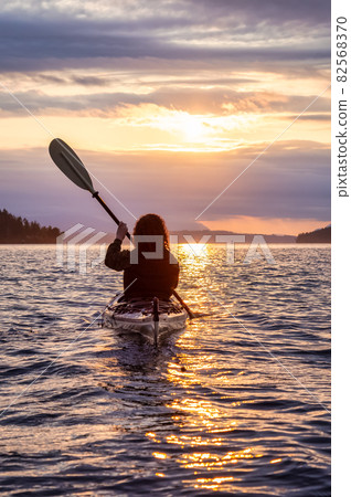 Adventurous Woman on Sea Kayak paddling in the Pacific Ocean. Adventurous Woman on Sea Kayak paddling in the Pacific Ocean. 82568370