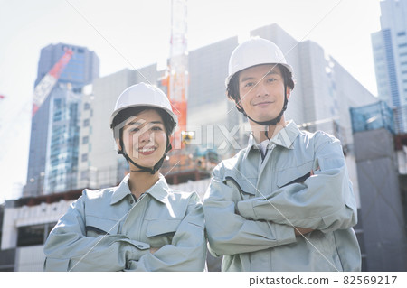 Men and women in work clothes standing at the construction site Men and women in work clothes standing at the construction site 82569217