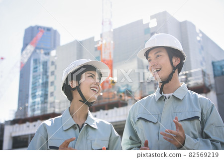 Men and women in work clothes standing at the construction site Men and women in work clothes standing at the construction site 82569219