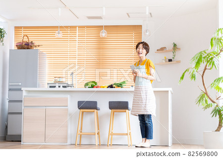 A smiling middle woman standing in the kitchen 82569800