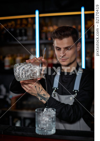 Professional male bartender makes an alcoholic cocktail Professional male bartender makes an alcoholic cocktail 82570419