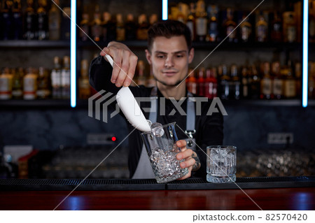Barman puts the ice cubes into a glass Barman puts the ice cubes into a glass 82570420