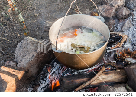 Tourist soup with vegetables boils in a cauldron 82572541