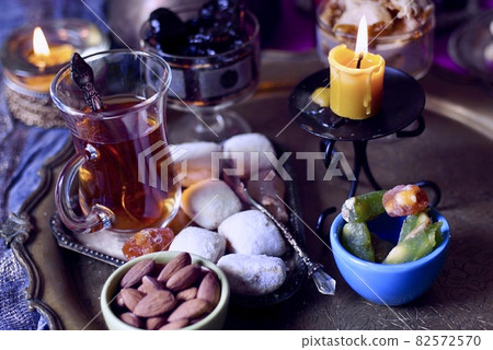 Black Turkish tea in lale with oriental sweets and dried fruits by candlelight 82572570