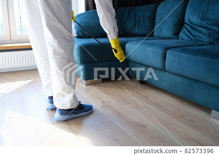 Person in protective suit and gloves is treating room from painful bacteria. Disinfection of premises concept Person in protective suit and gloves is treating room from painful bacteria. Disinfection of premises concept 82573396