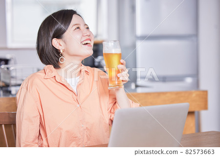 年輕女子在網上酒會上喝啤酒 年輕女子在網上酒會上喝啤酒 82573663