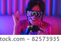 Neon  asian woman dancing. Fashion model woman in neon light, portrait of beautiful model with fluorescent make-up, Art and future design of female disco dancer posing in UV, colorful make up. 82573935