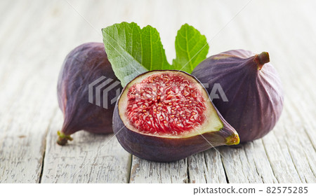 Figs with leaves on white wooden background Figs with leaves on white wooden background 82575285