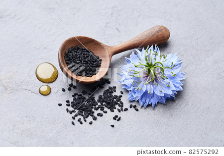 Black cumin seeds with nigella sativa flower on gray stone background 82575292