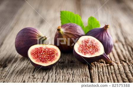 Figs with leaves on wooden background Figs with leaves on wooden background 82575388