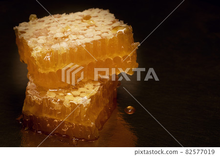 Yellow fresh honey in combs on black background it is flowing on table. Yellow fresh honey in combs on black background it is flowing on table. 82577019