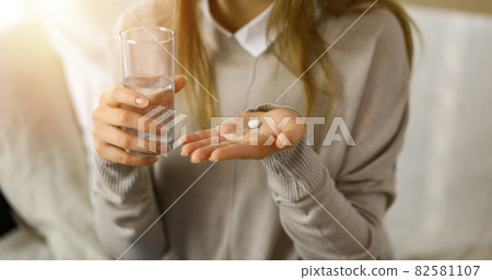 Close-up woman holding pills time to take medications, cure for headache. Medicine concept during self isolation and Coronavirus pandemic Close-up woman holding pills time to take medications, cure for headache. Medicine concept during self isolation and Coronavirus pandemic 82581107