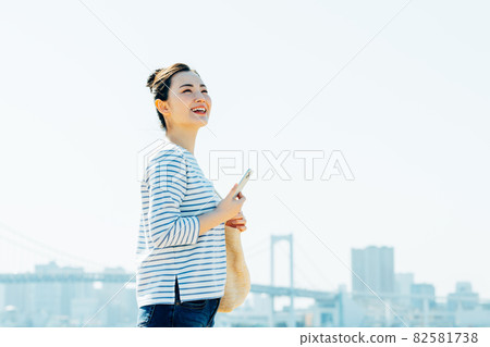 Young woman using a smartphone outdoors 82581738