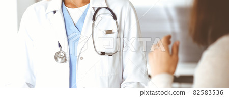 Unknown woman-doctor communicating with female patient. Physician checks medical history record and exam results, close-up. Medicine concept Unknown woman-doctor communicating with female patient. Physician checks medical history record and exam results, close-up. Medicine concept 82583536