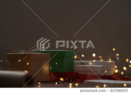 Gift boxes and festive packaging with christmas light on a table closeup Gift boxes and festive packaging with christmas light on a table closeup 82586093