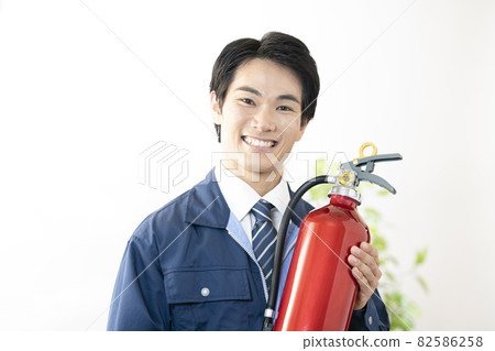 A man smiling with a fire extinguisher 82586258