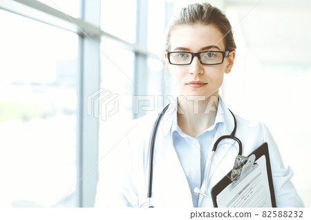 Beautiful woman doctor with stethoscope smiling charmingly and ready to help patients in the modern hospital. Medicine concept 82588232