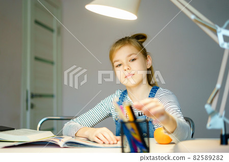 Beautiful girl working on her school project at home, education concept Beautiful girl working on her school project at home, education concept 82589282