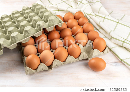 One brown chicken egg out of the full cardboard tray. One brown chicken egg out of the full cardboard tray. 82589283