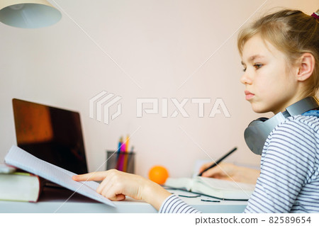 Teenage girl studying something using computer and headphones at home 82589654