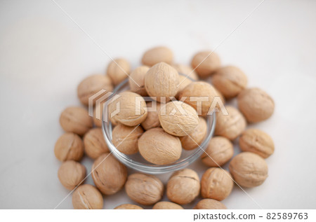 A lot of whole walnuts in a cup on a white background close-up. Healthy, organic food with a high content of protein and protein. 82589763