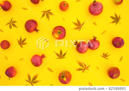 Pomegranate fuits with fall leaves isolated on yellow background. Flat lay Pomegranate fuits with fall leaves isolated on yellow background. Flat lay 82589891