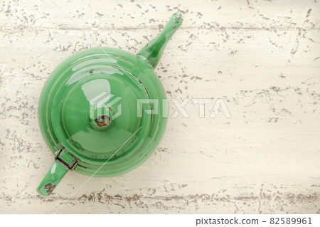 retro enameled green teapot on wooden table 82589961
