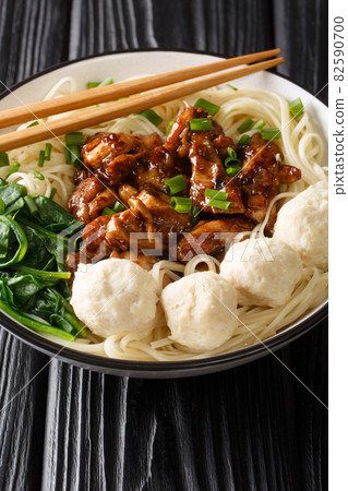 Mie ayam, mi ayam or bakmi ayam is a common Indonesian dish of seasoned noodles topped with diced chicken meat and meatball closeup in the bowl. Vertical 82590700