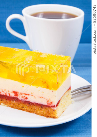 Creamy sweet sponge cake with different layers and jelly. Cup of coffee. Dessert for celebrations 82590745