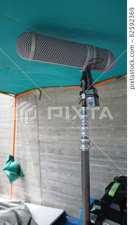 Microphone boom type. Sound recorder boom mic and tripod stand. Professional digital audio recording gear mic for making film or video movie production. Wind protection on boom mic. Movie industry Microphone boom type. Sound recorder boom mic and tripod stand. Professional digital audio recording gear mic for making film or video movie production. Wind protection on boom mic. Movie industry 82592369