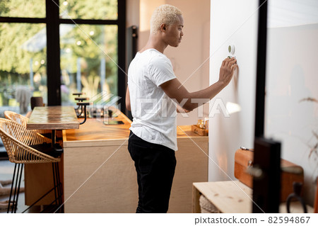 Black man choosing temperature on thermostat 82594867