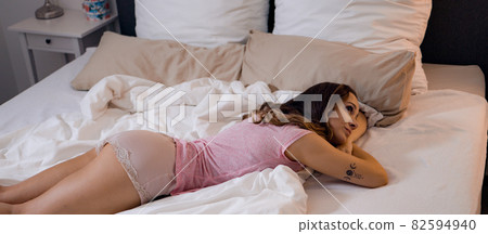 Young sexy woman lies relaxed on her bed Young sexy woman lies relaxed on her bed 82594940