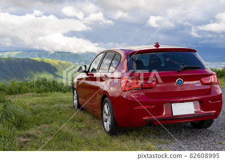 A red car parked in a parking lot with abundant nature in Aso Daikanbo 82608995