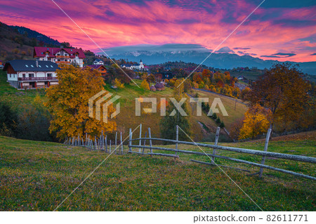 Magical autumn countryside scenery and snowy mountains at sunset, Romania Magical autumn countryside scenery and snowy mountains at sunset, Romania 82611771